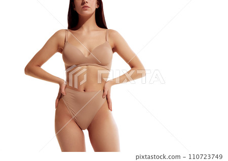 Cropped photo of slim female body with perfect smooth and healthy skin against white studio background. Model posing in lingerie Cropped photo of slim female body with perfect smooth and healthy skin against white studio background. Model posing in lingerie 110723749
