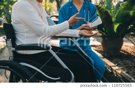 nurse with elderly man in wheelchair at park 110725565