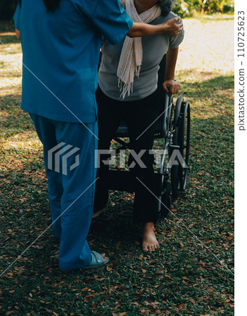 Young asian care helper with asia elderly woman on wheelchair relax together park outdoors to help and encourage and rest your mind with green nature. Help support yourself to learn to walk. walker Young asian care helper with asia elderly woman on wheelchair relax together park outdoors to help and encourage and rest your mind with green nature. Help support yourself to learn to walk. walker 110725623