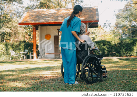 Young asian care helper with asia elderly woman on wheelchair relax together park outdoors to help and encourage and rest your mind with green nature. Help support yourself to learn to walk. walker Young asian care helper with asia elderly woman on wheelchair relax together park outdoors to help and encourage and rest your mind with green nature. Help support yourself to learn to walk. walker 110725625