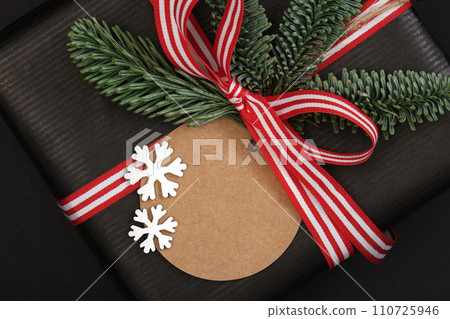 Gift box with fir tree sprig and label on dark background. Closeup. Space for your text 110725946