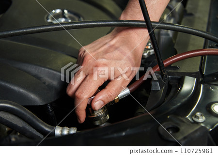 Hands of the master in cars and various car parts. Car engine, bumper, metal parts of the car. The master makes a car repair in a car repair shop. Hands of the master in cars and various car parts. Car engine, bumper, metal parts of the car. The master makes a car repair in a car repair shop. 110725981