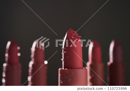 Red lipsticks with water drops on a dark background. 110725996