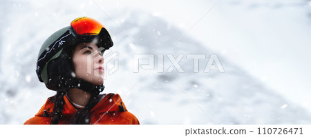 Panoramic photo of a Caucasian young woman in a ski helmet against the backdrop of a snowy landscape 110726471