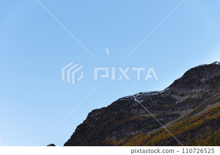 Clear daytime blue sky, mountains and waning white moon Clear daytime blue sky, mountains and waning white moon 110726525