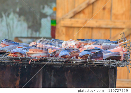 Fish cooking for sale at a local street food market in Tanzania 110727339