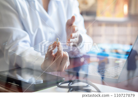 The doctor shows medicine in the form of a pill at the table. The doctor shows medicine in the form of a pill at the table. 110727879