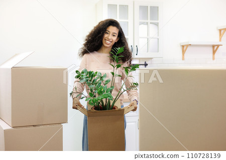 happy young African American woman is moving into new home. person stands among cardboard boxes  110728139