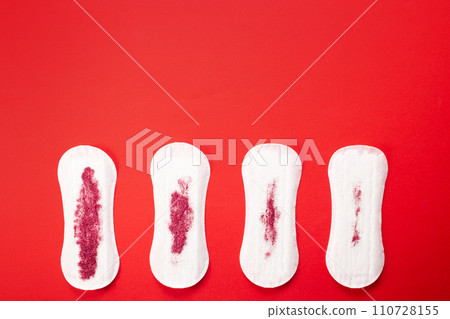 Feminine hygiene pads with red glitter on red background. First menstrual period concept Feminine hygiene pads with red glitter on red background. First menstrual period concept 110728155
