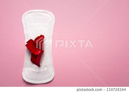 Feminine hygiene pad with red glitter and rose flower. First menstrual period concept on pink background 110728164