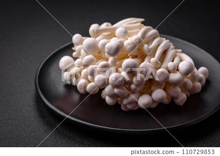 Small white edible beech mushrooms with salt and spices on a plain background Small white edible beech mushrooms with salt and spices on a plain background 110729853