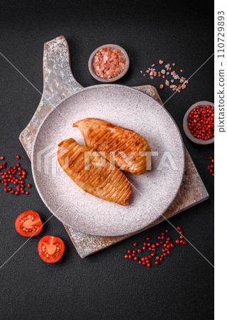 Delicious fresh grilled chicken fillet with spices and herbs on a dark concrete background 110729893