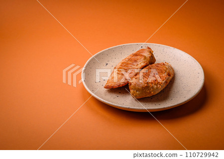 Delicious fresh grilled chicken fillet with spices and herbs on a dark concrete background 110729942