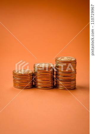 Round metal yellow coins folded in the form of columns on a plain colored background 110729967