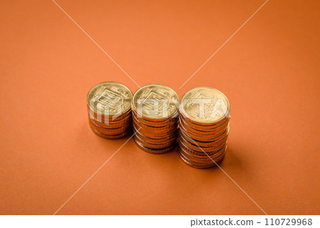 Round metal yellow coins folded in the form of columns on a plain colored background 110729968