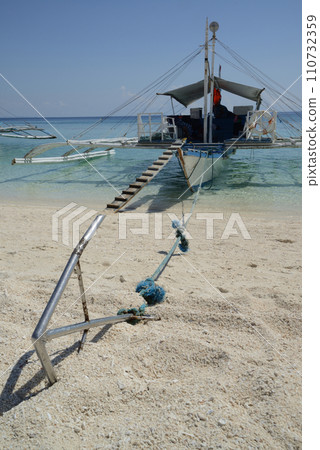 A traditional Filipino boat or Outrigger is moored at Kalanggaman Island on a beautiful clear day and anchored on a sandy beach. A traditional Filipino boat or Outrigger is moored at Kalanggaman Island on a beautiful clear day and anchored on a sandy beach. 110732359