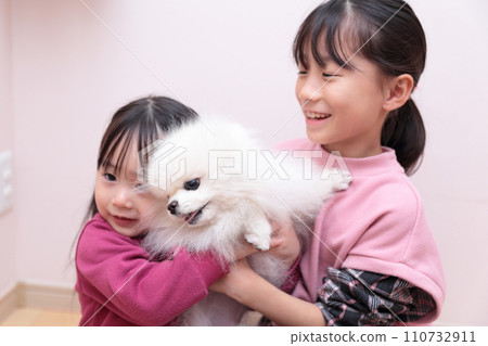 Sisters playing with their dog Pomeranian Sisters playing with their dog Pomeranian 110732911