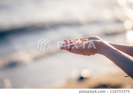 Palm picking up sea glass at sea 110733375