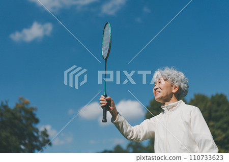 A woman in her 60s playing badminton outdoors 110733623