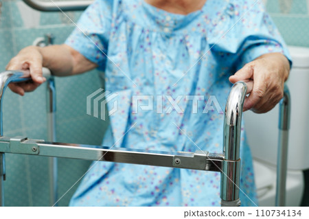 Asian elderly old woman patient use toilet support rail in bathroom, handrail safety grab bar, security in nursing hospital. 110734134