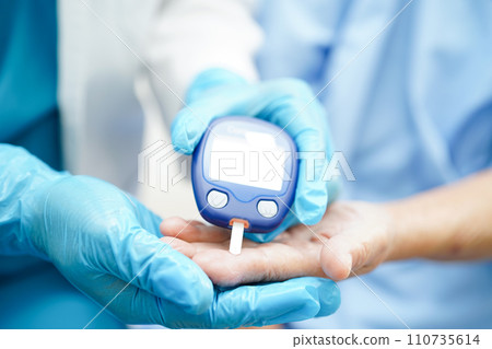 Asian doctor using digital glucose meter for check sample blood sugar level to treatment diabetes. 110735614