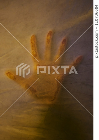 Hand pressing through fabric as horror background. Hand pressing through fabric as horror background. 110736684
