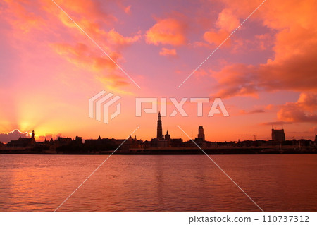 Silhouette of the city at sunrise from the opposite bank of the Escaut River flowing through Antwerp, Belgium, Western Europe 110737312