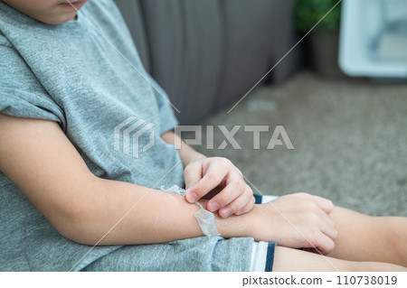 Little Asian boy's hands peeling off dry skin on his arm. Skin problems. Little Asian boy's hands peeling off dry skin on his arm. Skin problems. 110738019