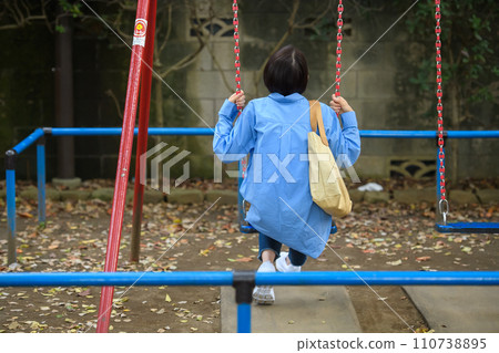 A woman killing time in the park, rear view 110738895