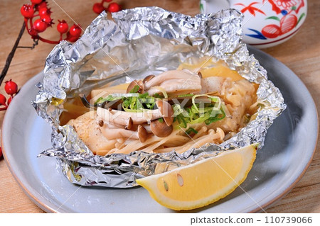 Grilled cod in foil, easy recipe, served with lemon. 110739066