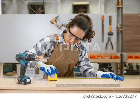 happy women enjoy working designer in wood workshop. Joiner wood apron worker furniture hand crafted factory. happy women enjoy working designer in wood workshop. Joiner wood apron worker furniture hand crafted factory. 110739277