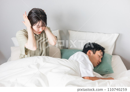 妻子因丈夫在床上打呼嚕和說夢話而睡眠不足。 妻子因丈夫在床上打呼嚕和說夢話而睡眠不足。 110740259