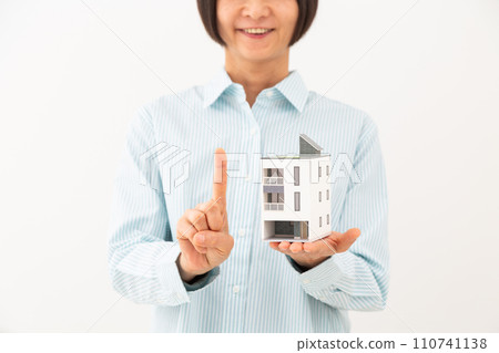 一位中年婦女拿著獨立屋模型,舉起食指 一位中年婦女拿著獨立屋模型,舉起食指 110741138