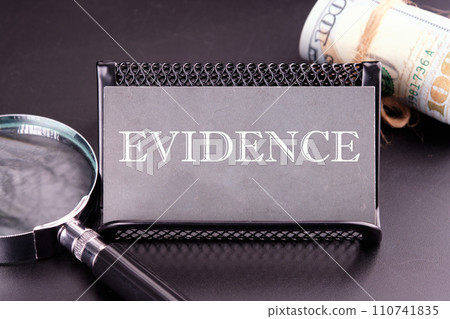 EVIDENCE text on the business card next to the money, a magnifying glass on a black background EVIDENCE text on the business card next to the money, a magnifying glass on a black background 110741835