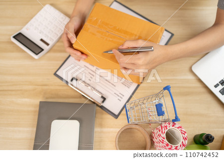 Sell products online, Top view of handwritten notes of customer details and address on postal box in preparation for delivery according to the information, Packing box, Freelance working. Sell products online, Top view of handwritten notes of customer details and address on postal box in preparation for delivery according to the information, Packing box, Freelance working. 110742452