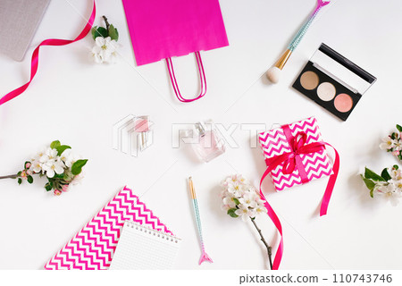 Women's workplace of a fashion blogger. Cosmetics, a gift box with a bow and notebooks. Flat lay on a white background 110743746