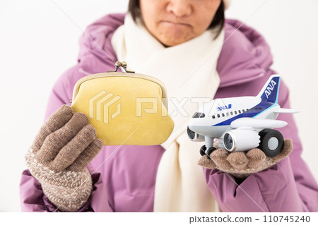 A middle-aged woman in winter clothes worries about holding a wallet and an airplane. A middle-aged woman in winter clothes worries about holding a wallet and an airplane. 110745240