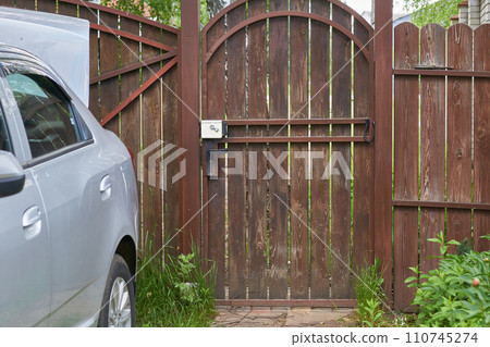 Wooden gate with a brown fence and a car in the village 110745274