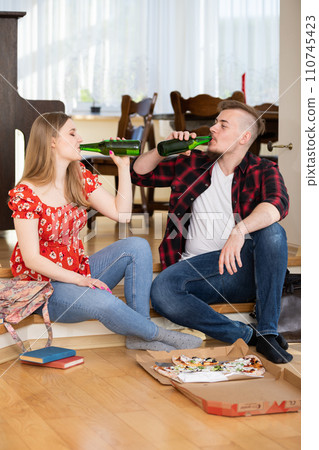 A boy and a girl drink beer from green bottles without labels. A boy and a girl drink beer from green bottles without labels. 110745423