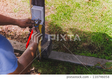 Electrician's hand stripping electrical wires with stationery knife. 110746058