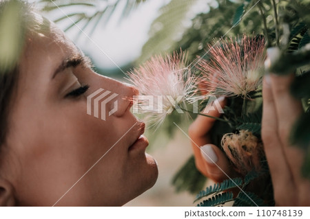 Beauty portrait of happy woman closeup. Young girl smelling Chinese acacia pink blossoming flowers. Portrait of young woman in blooming spring, summer garden. Romantic vibe. Female and nature 110748139