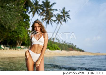 Fit solo female traveler enjoys serene beach alone. Adventure-seeking woman in swimwear relaxes by tropical sea. Single lady explores coastal paradise, healthy lifestyle on vacation. Fit solo female traveler enjoys serene beach alone. Adventure-seeking woman in swimwear relaxes by tropical sea. Single lady explores coastal paradise, healthy lifestyle on vacation. 110750411