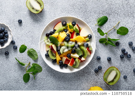 Fruit and berry salad with mango, kiwi, apple, blueberry and fresh mint leaves. Healthy food, diet. Top view 110750518