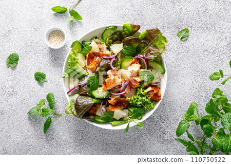 Salad with grilled salmon, fresh green salad leaves, cucumber, red onion, mint and pineapple. Healthy lunch salad for keto diet. Top view Salad with grilled salmon, fresh green salad leaves, cucumber, red onion, mint and pineapple. Healthy lunch salad for keto diet. Top view 110750522
