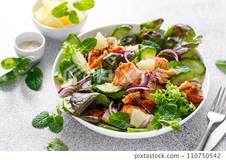 Salad with grilled salmon, fresh green salad leaves, cucumber, red onion, mint and pineapple. Healthy lunch salad for keto diet 110750542