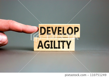 Develop agility symbol. Concept words Develop agility on wooden blocks on a beautiful grey table grey background. Businessman hand. Business, support and develop agility concept. Copy space. 110751249