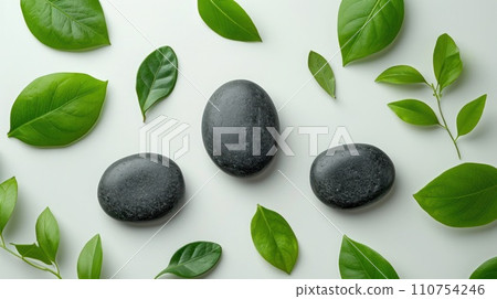 top view of three black stones and leaves on white background top view of three black stones and leaves on white background 110754246