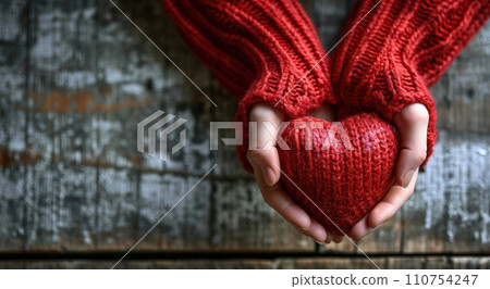 hands in red sweater and red heart on wooden background 110754247