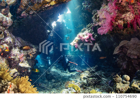 Scuba Diver Swimming into Underwater Cave With Sunrays. Young Man DIver Eploring Sea Life. 110754690