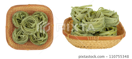 Raw tagliatelle green pasta with spinach in a wicker basket isolated on white background. Top view. Flat lay 110755348
